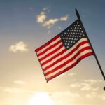 American flag waved against sunset sky.