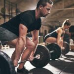 Man and woman lifting barbells in gym.