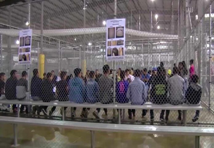 1229072206 featured image People sitting on benches inside a fenced facility.