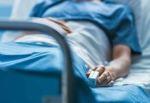 Person lying in hospital bed with monitor attached