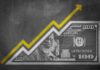 Yellow arrow rising above a one hundred dollar bill