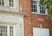 Brick school building with windows and foliage.