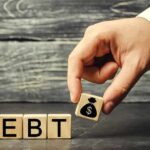 Hand replacing debt block with money symbol block