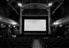 Empty theater with ornate decor and projection screen.