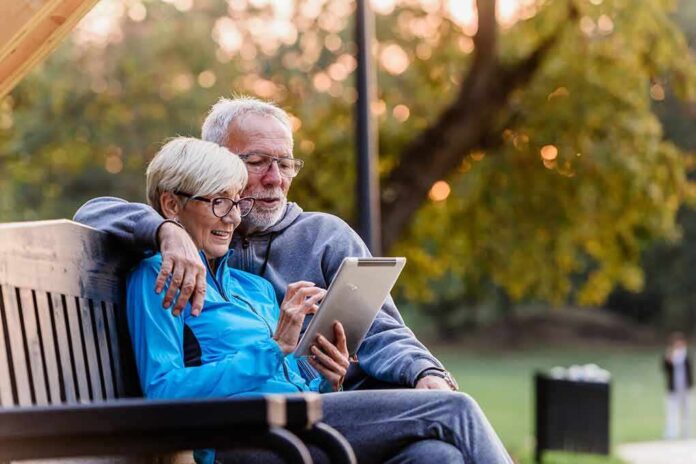 1626520732 featured image Older couple sitting on bench using tablet outdoors