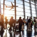 Passengers waiting at airport gate with airplane outside window