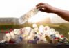 Hand placing plastic bottle in recycling bin.
