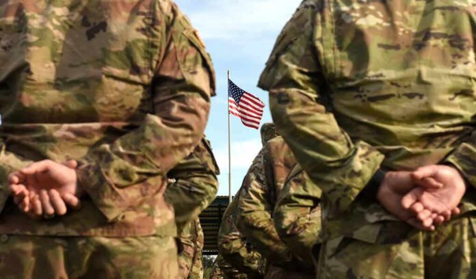 1507031819 featured image Soldiers stand in formation with American flag in background.