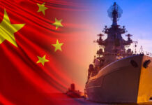 Chinese flag overlaps battleship and submarine at sunset