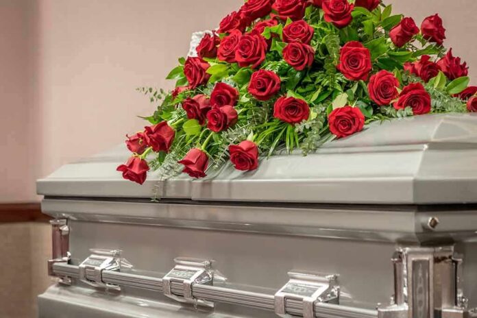 1734828347 featured image Silver casket with red rose arrangement on top.