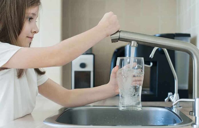1742845301 featured image Girl filling glass with water from kitchen faucet