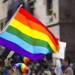 People holding and waving a rainbow flag