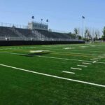 Empty football field with bleachers in background