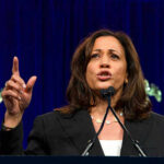 Woman speaking passionately at a podium, gesturing upward