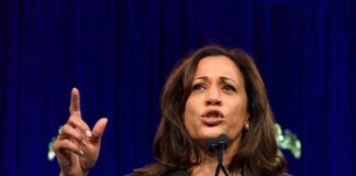 Woman speaking passionately at a podium gesturing upward