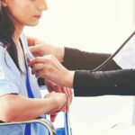 Doctor examining patient with stethoscope in hospital