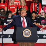 Politician speaking at rally with supporters behind him