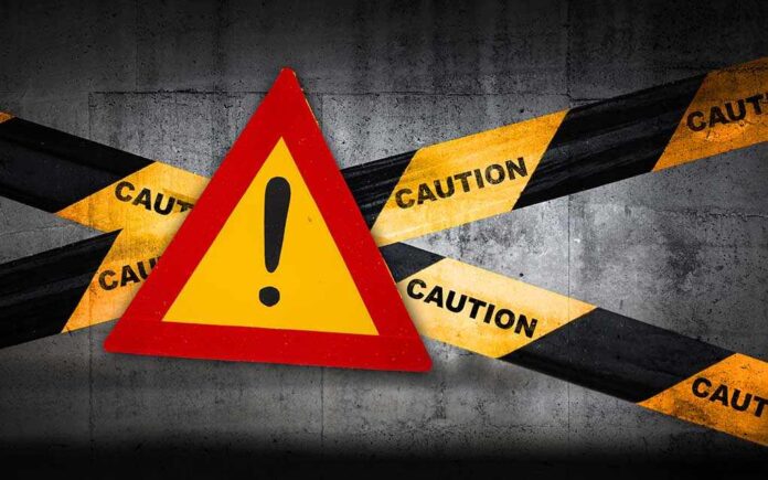 Warning sign with caution tape against a concrete background