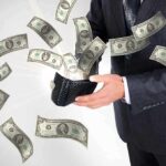 A businessman holding a wallet with money flying out
