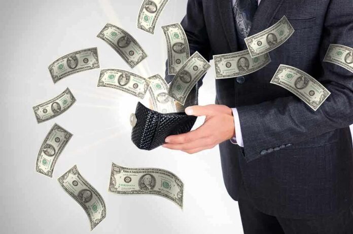 A businessman holding a wallet with money flying out