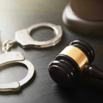 Gavel and handcuffs on a dark surface