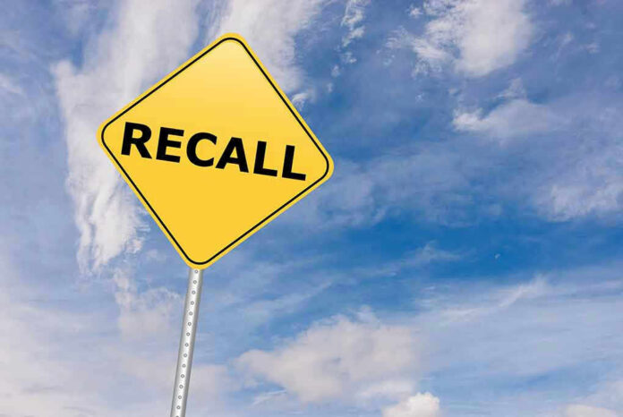 Yellow recall sign against blue cloudy sky