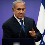 Man in suit giving speech in front of Israeli flag
