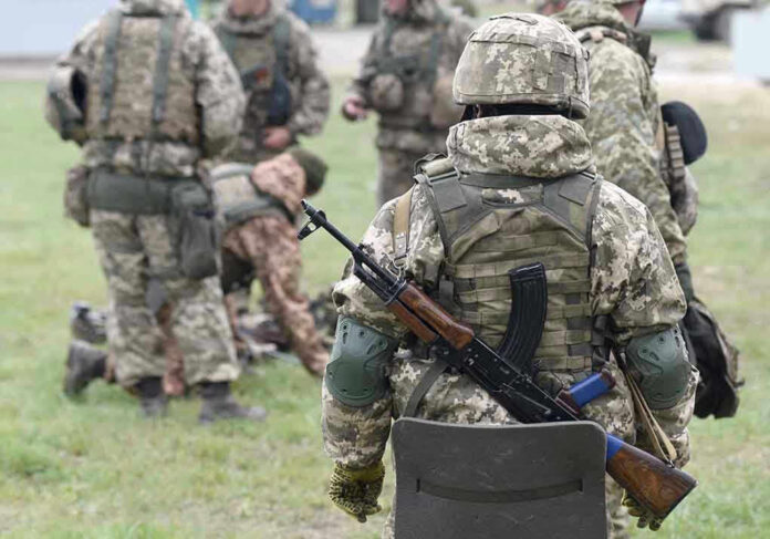 2057061182 Soldiers in camouflage gear gathered on grass field