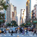 Busy city street with pedestrians cars and tall buildings