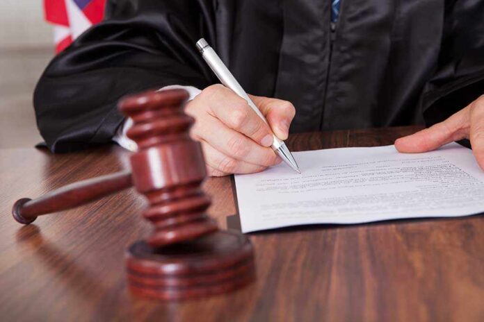 A judge signing a legal document with a gavel in the foreground