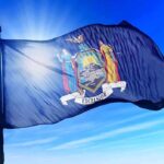New York state flag waving against a blue sky