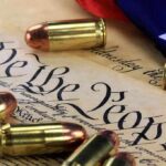 Close up of bullets surrounding a historical document with the phrase We the People