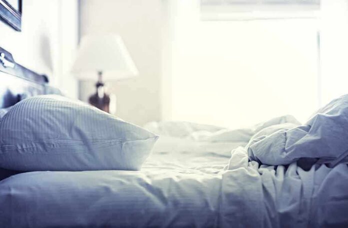 A cozy unmade bed with soft pillows and bedding in a well lit room