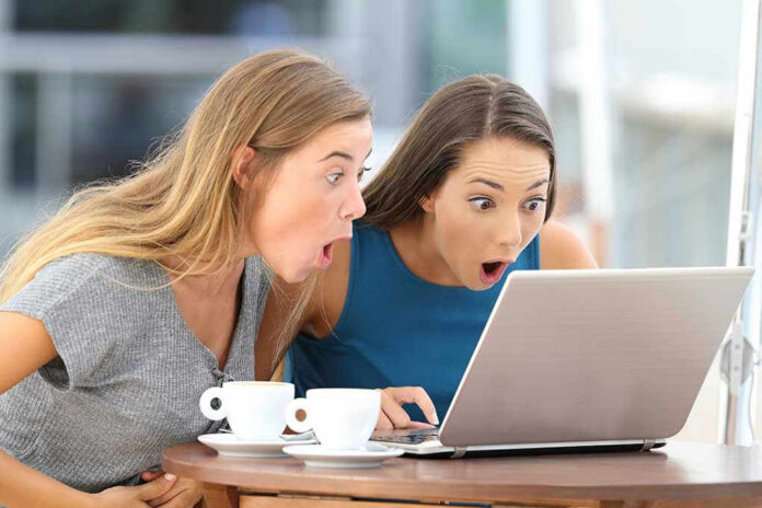 Two women surprised while looking at a laptop.
