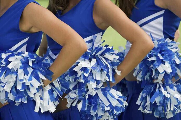 Cheerleaders in blue and white uniforms holding pom poms