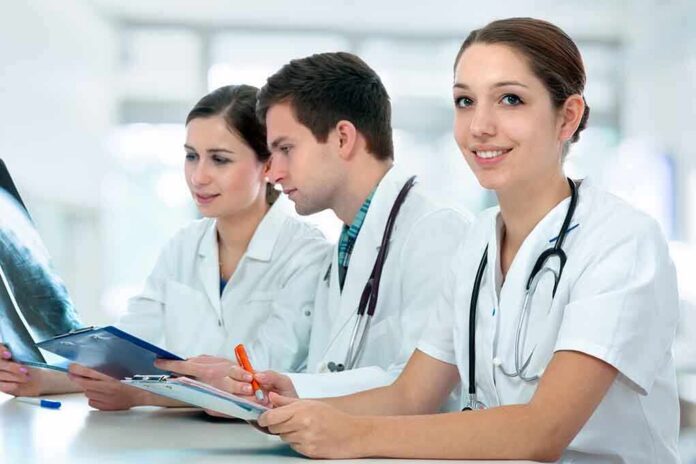 Three medical professionals reviewing patient xrays in a healthcare setting
