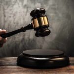 A hand holding a gavel above a wooden block