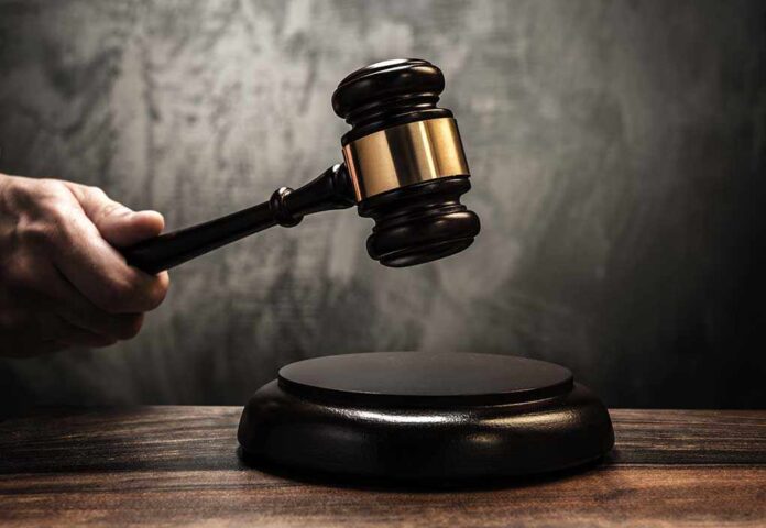 shutterstock_155711243.jpg A hand holding a gavel above a wooden block