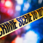 Yellow crime scene tape with blurred lights background.