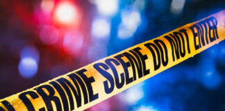 Yellow crime scene tape with blurred lights background.