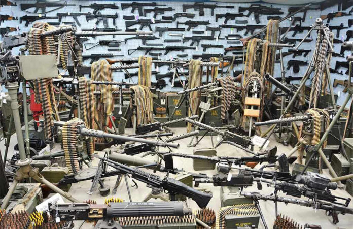 Room filled with various firearms and ammunition belts.