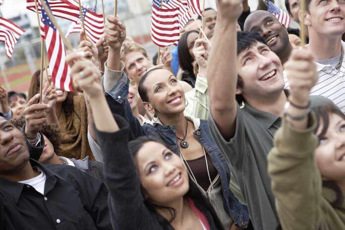 A diverse group of people joyfully waving American flags in celebration