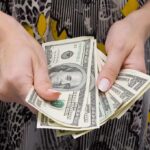 Hands holding a fan of hundred dollar bills