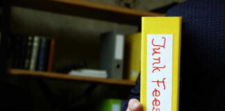 Hand holding folder labeled Junk Fees bookshelf background