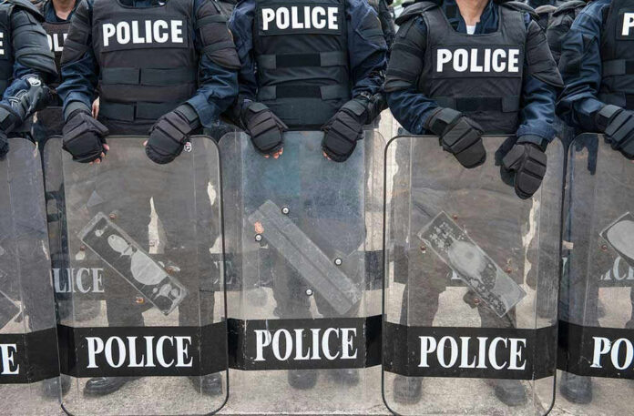 Police officers in riot gear holding shields.