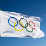 Olympic Gold Sparks Outrage – Critics Ignore Win Olympic flag waving against clear blue sky.