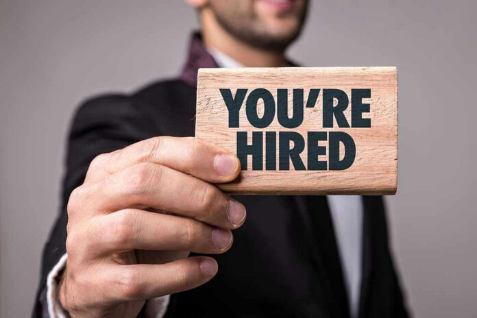 Person holding a Youre Hired sign.