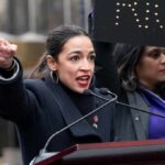 AOC’s 2028 Gamble Could Ignite GOP Landslide A woman passionately speaking at a rally with a sign in the background