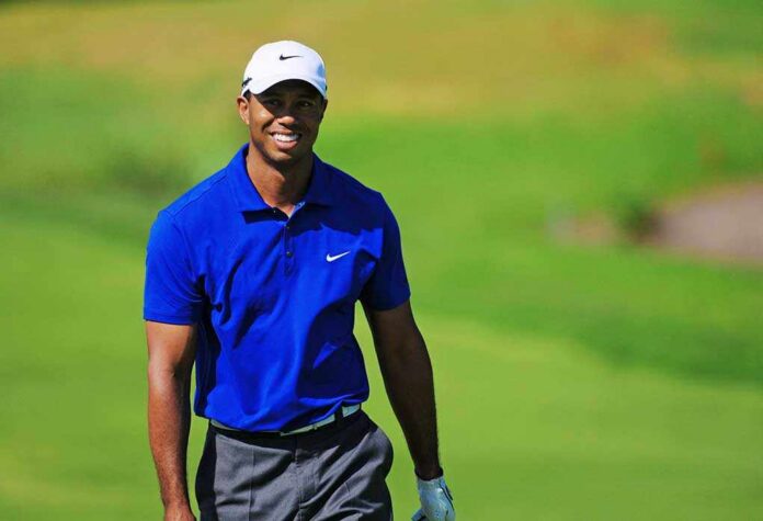 A smiling golfer wearing a blue shirt and white cap on a green golf course
