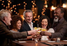 Toxic People Quietly Accelerate Aging People laughing while clinking glasses at a bar